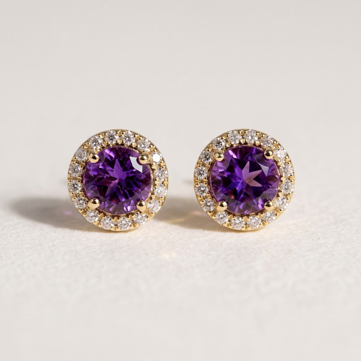 Pair of 14K yellow gold round amethyst and diamond halo stud earrings with 1.12 TCW gemstones