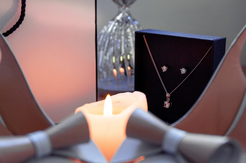 Luxury jewelry gift box opened revealing sparkling diamond stud earrings and gold pendant