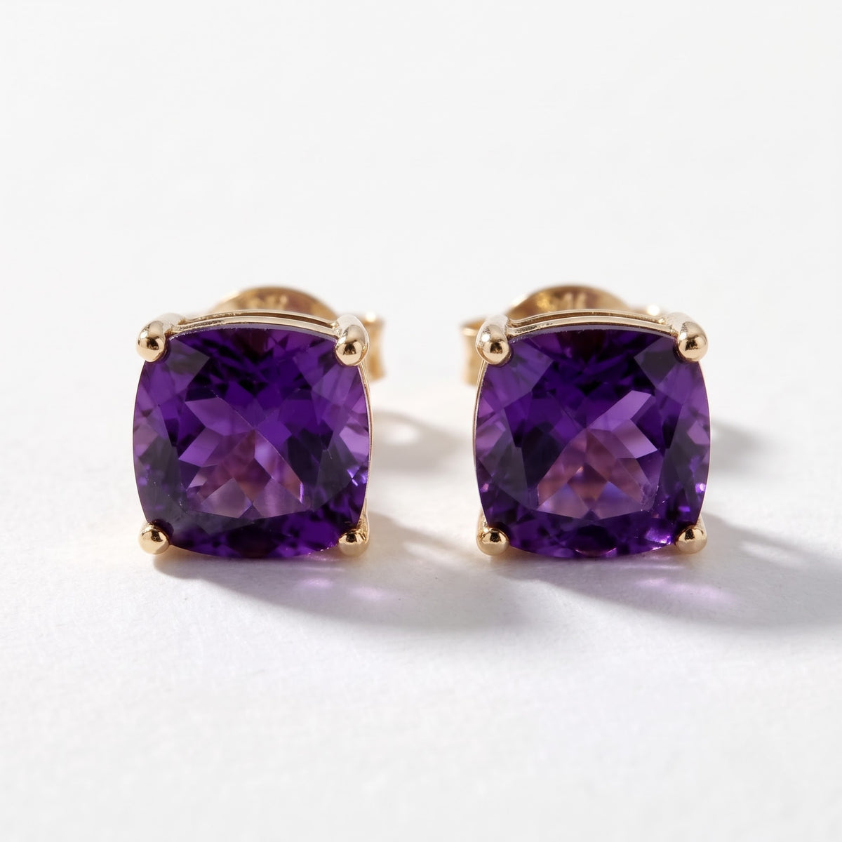 Pair of 14K yellow gold cushion-cut amethyst stud earrings with 4.25 TCW purple gemstones in four-prong basket settings