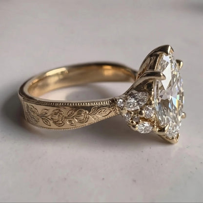 Close-up of a yellow gold Art Deco engagement ring with a marquise center stone, floral cluster accents, and an engraved band.