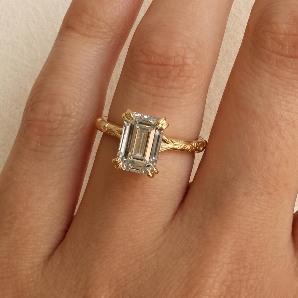 A close-up of a hand wearing a gold ring with a large emerald-cut clear gemstone.